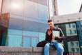 Arabian student using smartphone outside. Young guy looks at phone in front of modern building after classes Royalty Free Stock Photo