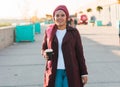 Young Arabic muslim woman in hijab walking at street seafront and drinking coffee take away