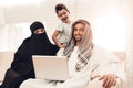 Young Arabic Family Using Laptop on Sofa at Home