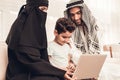 Young Arabic Family Using Laptop on Sofa at Home.
