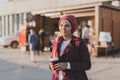 Young Arabic muslim woman in hijab walking at street seafront and drinking coffee take away