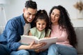 Young Arabic Parents Reading Book With Their Cute Little Daughter At Home Royalty Free Stock Photo