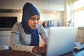 Young Arabic woman working on a laptop in her kitchen Royalty Free Stock Photo