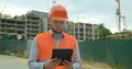 Young architect or builder man standing with digital touchpad on the construction site and analyzing scheme project plan Royalty Free Stock Photo