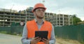 Young architect or builder man standing with digital touchpad on the construction site and analyzing scheme project plan Royalty Free Stock Photo