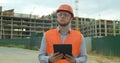 Young architect or builder man standing with digital touchpad on the construction site and analyzing scheme project plan Royalty Free Stock Photo