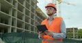 Young architect or builder man standing with digital touchpad on the construction site and analyzing scheme project plan Royalty Free Stock Photo