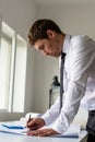 Young architect standing at his office desk leaning in to work o Royalty Free Stock Photo