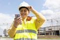 Young Architect woman in white hardhat and safety vest with digital tablet using smartphone outdoors. Female engineer Royalty Free Stock Photo