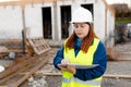 Young architect woman in white hardhat and safety vest using digital tablet outdoors. Female construction engineer Royalty Free Stock Photo