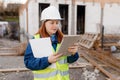 Young architect woman in white hardhat and safety vest using digital tablet outdoors. Female construction engineer Royalty Free Stock Photo