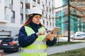 Young architect woman in white hardhat and safety vest using digital tablet outdoors. Female construction engineer Royalty Free Stock Photo