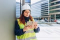 Young architect woman in white hardhat and safety vest using digital tablet outdoors. Female construction engineer Royalty Free Stock Photo