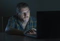 Young aroused and excited sex addict man watching mobile online in laptop computer light night at home in Royalty Free Stock Photo