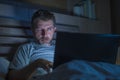 Tired and stressed workaholic man working late night exhausted on bed busy with laptop computer feeling sleepy suffering business Royalty Free Stock Photo