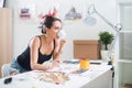 Young artist drawing watercolor picture sideview, holding cup of coffee