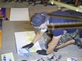 A young artist paints a picture of multicolored spray paint at night in front of everybody. A young guy in a respirator.