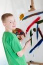 Young artist smiles over his shoulder near easel
