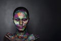 Young artistic woman in black paint and colourful powder. Glowing dark makeup. Creative body art on the theme of space