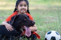 A young Asain girl playing football with her big black dog outside the grass ground in the yard in the evening Royalty Free Stock Photo