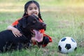 A young Asian girl playing football with her big black dog outside the grass ground in the yard in the evening Royalty Free Stock Photo