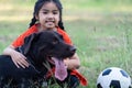 A young Asian girl playing football with her big black dog outside the grass ground in the yard in the evening Royalty Free Stock Photo