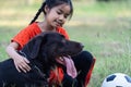 A young Asian girl playing football with her big black dog outside the grass ground in the yard in the evening Royalty Free Stock Photo