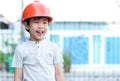 Young Asia boy in gray T shirt wearing a orange safety helmet standing in the garden at home. Feeling happy, fun and smile
