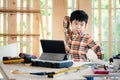Young Asia boy wearing a shirt and standing at the table at home. He is bored with his job. There is more equipment tablet,