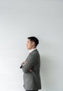 Young Asia businessman stands crossed its back and looking forward with confidence vision against a gray wooden backdrop