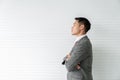 Young Asia businessman stands crossed its back and looking forward with confidence vision against a gray wooden backdrop