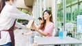 Young Asia businesswoman customer take out food bag order from restaurant staff wearing face mask and gloves in coffee shop.