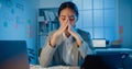 Young Asia businesswoman sit with laptop and tablet on desk rubbing eye feel pain and tired from overwork in office at night. Royalty Free Stock Photo