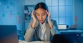 Young Asia businesswoman sit with laptop and tablet on desk rubbing eye feel pain and tired from overwork in office at night. Royalty Free Stock Photo