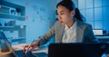 Young Asia cheerful professional woman sitting on desk focus concentrate working on laptop and digital tablet check detail final