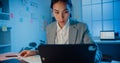 Young Asia cheerful professional woman sitting on desk focus concentrate working on laptop and digital tablet check detail final