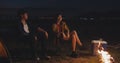 Young asia couple backpackers enjoying in camping at night near campfire on beach. Male and female traveler relaxing and talking Royalty Free Stock Photo