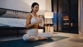 Young Asia lady doing yoga exercise working out and drinking pure water in living room at home night. Sport and recreation Royalty Free Stock Photo