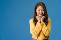 Young Asia lady with positive expression, smile broadly, dressed in casual clothing and close your eyes over blue background.