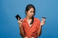 Young Asia lady using phone and credit bank card with negative expression, excited screaming, cry emotional angry in casual cloth