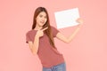 Young asia smiling woman holding advertising sign board and pointing finger. Isolated portrait on pink background with copy space Royalty Free Stock Photo