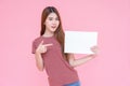 Young asia smiling woman holding advertising sign board and pointing finger. Isolated portrait on pink background with copy space Royalty Free Stock Photo