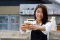 Young asia woman barista holding a diaposable coffee cup with sm