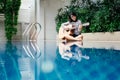 Young woman hold guitar classic in her hand and sitting beside p Royalty Free Stock Photo