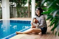 Young woman hold guitar classic in her hand and sitting beside p Royalty Free Stock Photo