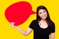 Young Asia woman holding red speech bubble on yellow background. Asian female show sign speech bubble banner, pretty girl get Royalty Free Stock Photo