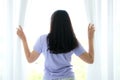 Young Asia woman standing in front of the window in the bedroom and looking outside Royalty Free Stock Photo