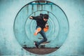 Young Asian active man jumping and kicking action, circle looping wall background. Extreme sport activity concept