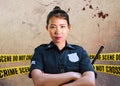 Young Asian American police officer standing serious in custody of crime scene for preserving evidence at do not cross police line