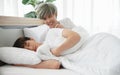 Young Asian attractive gay man smile and provoke his boyfriend by hand put on his shoulder while his lover sleeping on bed in the Royalty Free Stock Photo